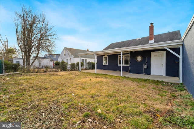 view of front of house featuring fence, a chimney, a front yard, and a patio area