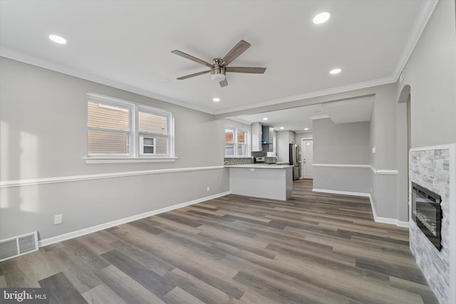 unfurnished living room featuring visible vents, baseboards, ornamental molding, and a ceiling fan