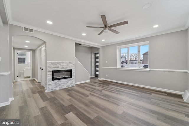 unfurnished living room featuring baseboards, a ceiling fan, visible vents, and arched walkways