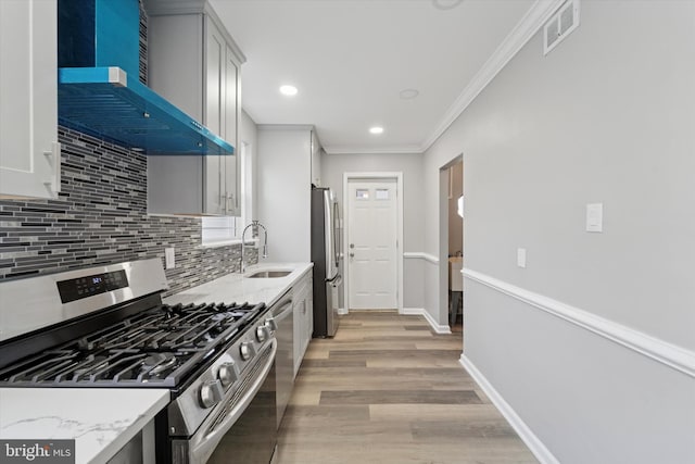 kitchen with visible vents, decorative backsplash, stainless steel appliances, wall chimney exhaust hood, and a sink