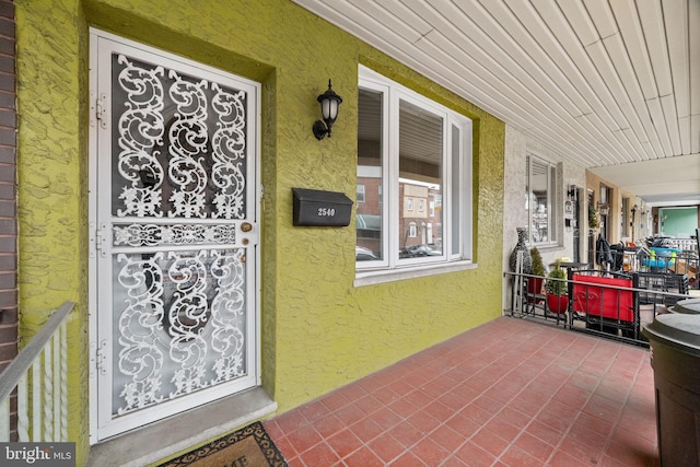 doorway to property with stucco siding and a porch