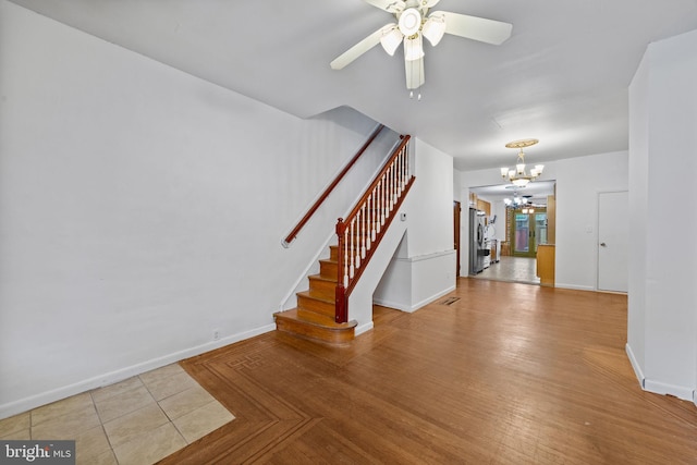 interior space with stairway, ceiling fan with notable chandelier, visible vents, and baseboards