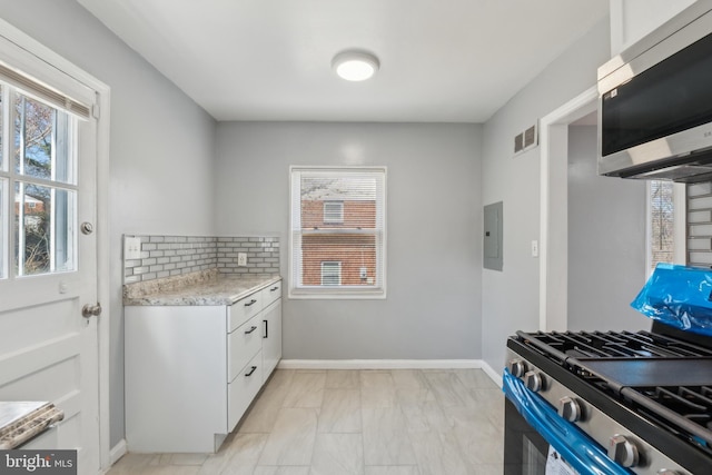 kitchen with electric panel, decorative backsplash, plenty of natural light, and stainless steel appliances