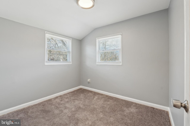 carpeted empty room with vaulted ceiling and baseboards