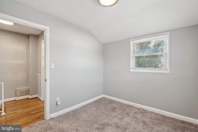 interior space with visible vents, baseboards, light colored carpet, and vaulted ceiling