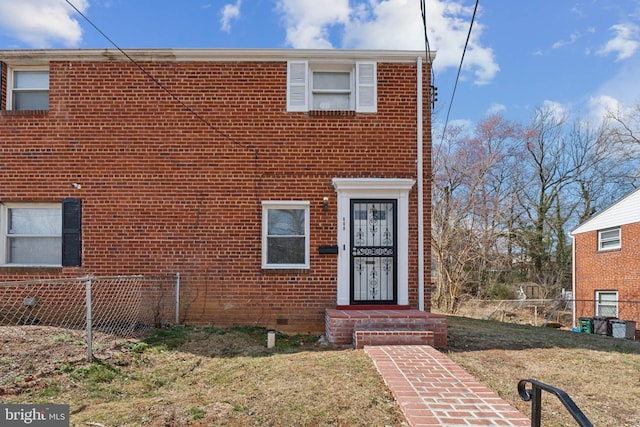 townhome / multi-family property featuring brick siding, a front yard, and fence