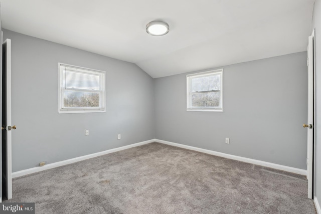 interior space with carpet flooring, vaulted ceiling, multiple windows, and baseboards