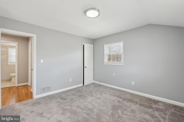 unfurnished bedroom featuring carpet flooring, multiple windows, baseboards, and visible vents