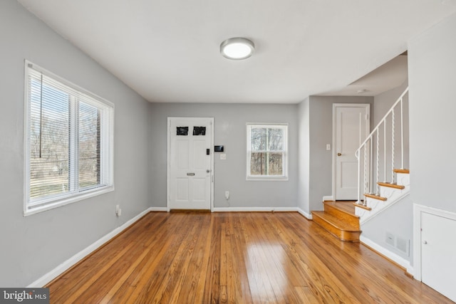 foyer with a wealth of natural light, visible vents, baseboards, and hardwood / wood-style flooring