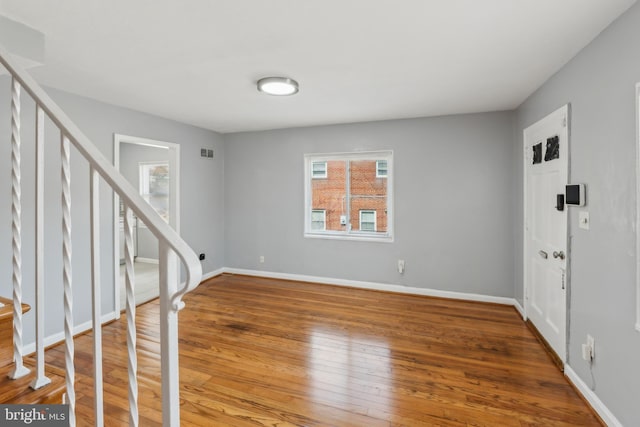 foyer featuring visible vents, stairway, baseboards, and wood finished floors