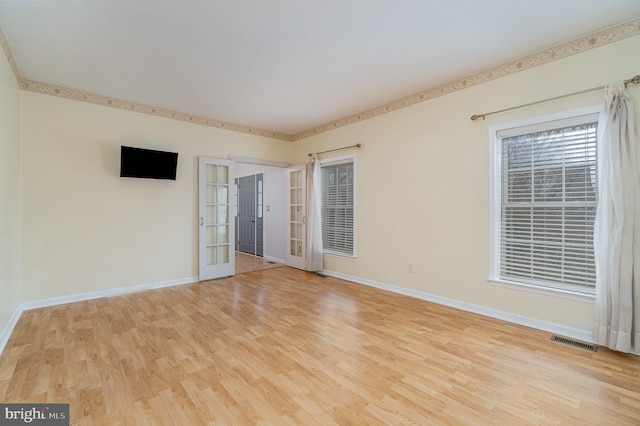 unfurnished room with visible vents, baseboards, light wood-style flooring, and french doors