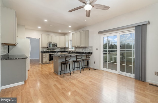 kitchen with a kitchen bar, visible vents, a ceiling fan, stainless steel appliances, and a peninsula