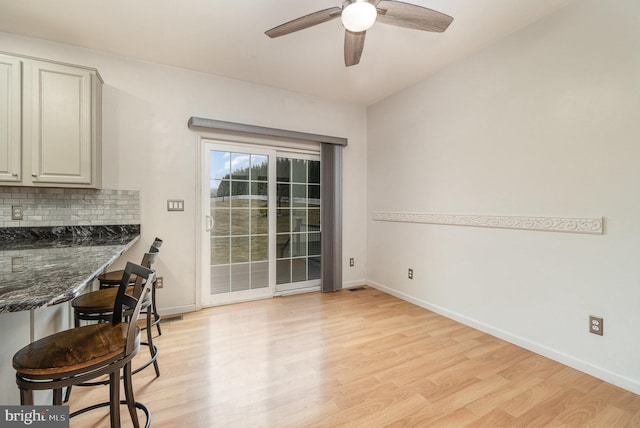 dining space with baseboards, light wood-type flooring, and ceiling fan