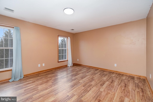 empty room with baseboards, visible vents, and light wood-type flooring