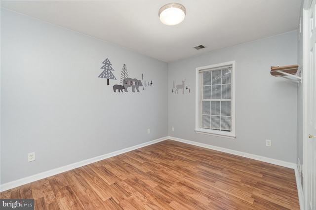 spare room with visible vents, baseboards, and wood finished floors