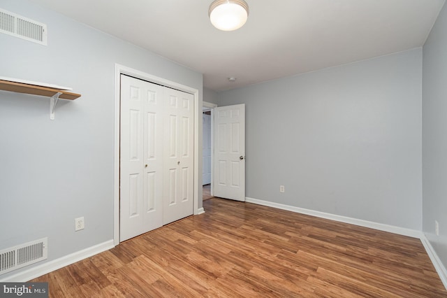 unfurnished bedroom with a closet, baseboards, visible vents, and light wood finished floors