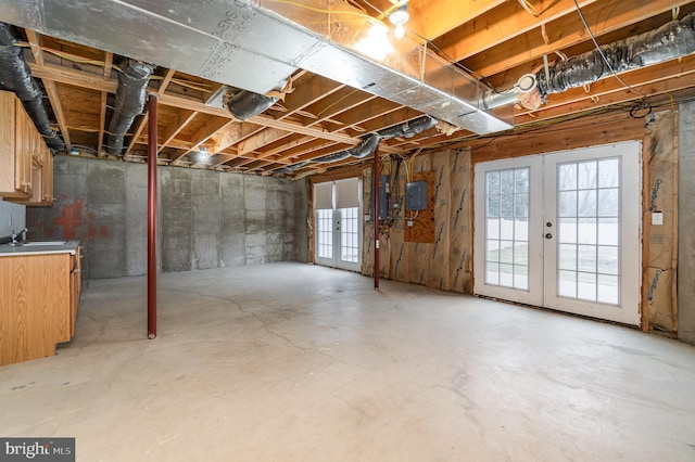 basement featuring electric panel, french doors, and a sink