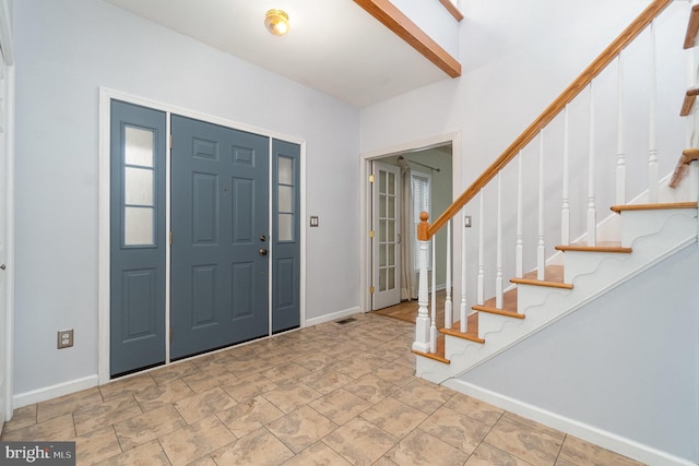 foyer with stairway, visible vents, and baseboards