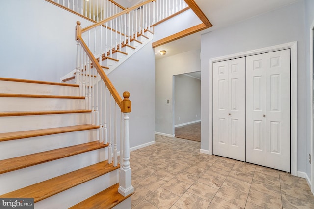 stairway featuring a high ceiling and baseboards