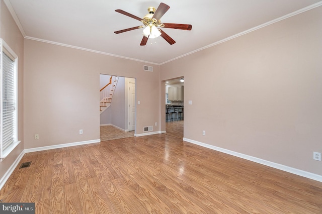 empty room featuring light wood finished floors, visible vents, stairs, and ceiling fan