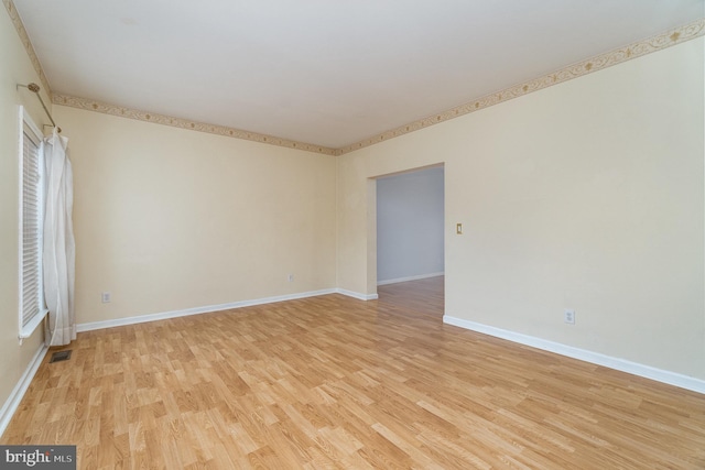 spare room with visible vents, light wood-style flooring, and baseboards