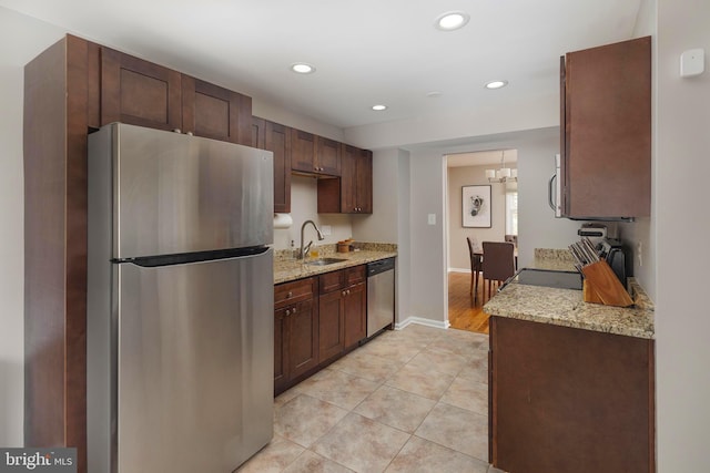 kitchen with light stone countertops, light tile patterned floors, recessed lighting, stainless steel appliances, and a sink