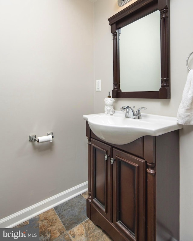 bathroom featuring vanity, stone finish flooring, and baseboards