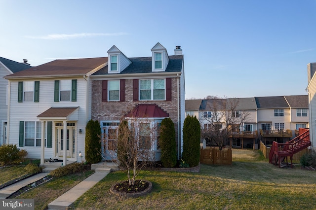 townhome / multi-family property featuring brick siding, a front lawn, and fence