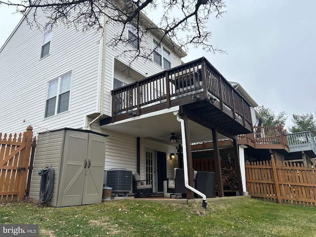 back of house featuring an outbuilding, a ceiling fan, fence, a yard, and a storage unit