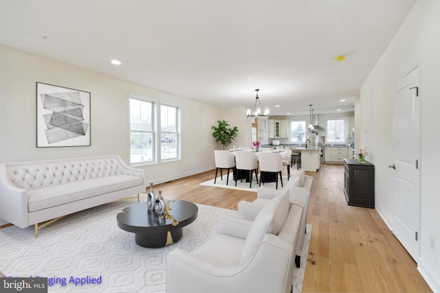 living area featuring recessed lighting, light wood-style floors, baseboards, and a chandelier