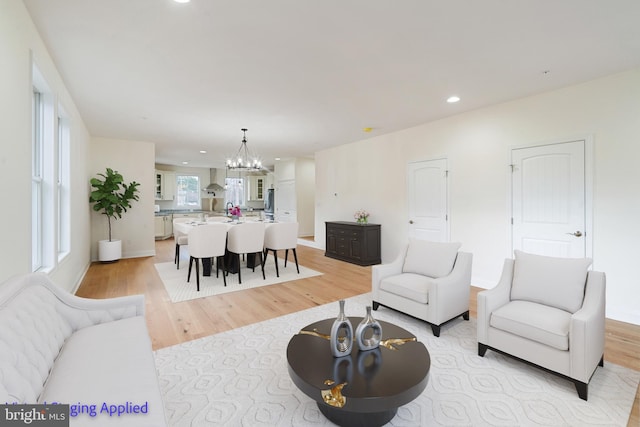 living room featuring a notable chandelier, light wood-style floors, and recessed lighting