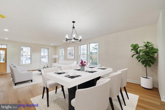 dining area featuring an inviting chandelier, plenty of natural light, light wood-style floors, and baseboards