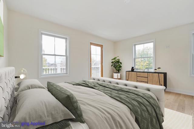 bedroom with baseboards, multiple windows, and wood finished floors