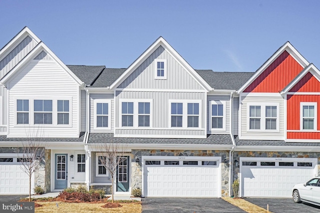 townhome / multi-family property featuring board and batten siding, a shingled roof, a garage, stone siding, and driveway