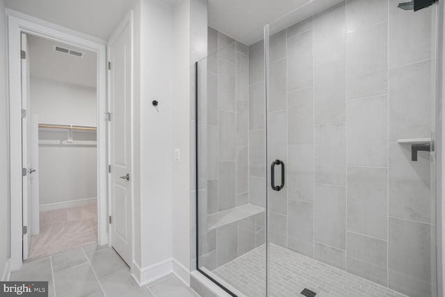 full bath with tile patterned flooring, visible vents, a shower stall, a walk in closet, and baseboards