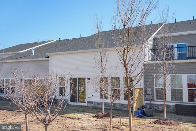 rear view of house with a shingled roof and a balcony