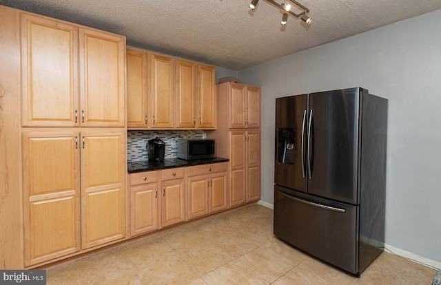 kitchen with light tile patterned flooring, decorative backsplash, a textured ceiling, stainless steel microwave, and fridge with ice dispenser