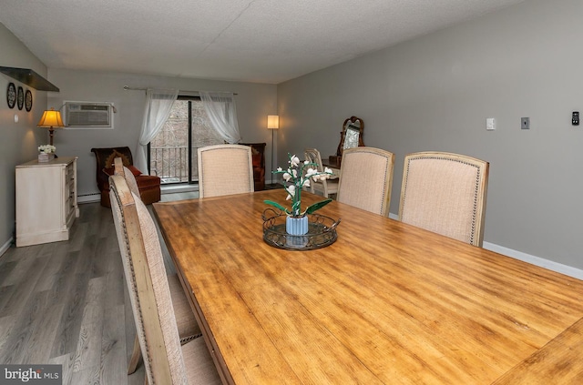 dining area with an AC wall unit, a textured ceiling, wood finished floors, a baseboard radiator, and baseboards