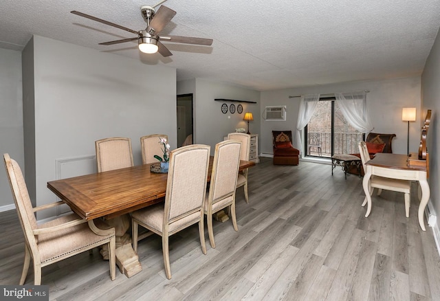 dining room with a wall mounted AC, a textured ceiling, light wood-type flooring, and ceiling fan