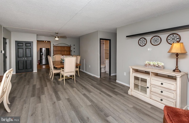 dining space with baseboards, a textured ceiling, wood finished floors, and a ceiling fan