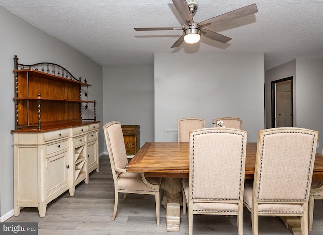 dining room featuring baseboards, a textured ceiling, a ceiling fan, and light wood finished floors