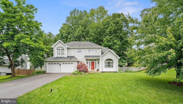 traditional-style home with driveway, a front lawn, a garage, and fence