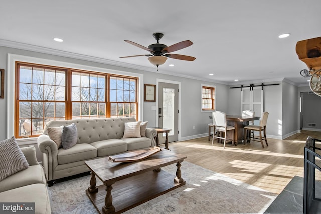 living room featuring a ceiling fan, recessed lighting, a barn door, crown molding, and light wood finished floors