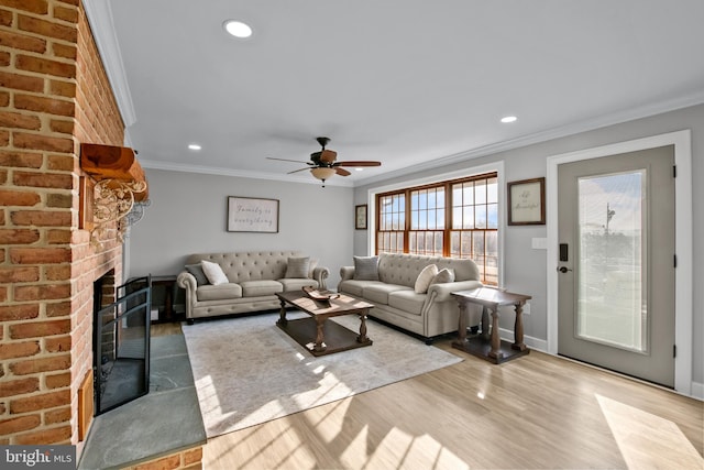 living area with a fireplace, crown molding, ceiling fan, and wood finished floors