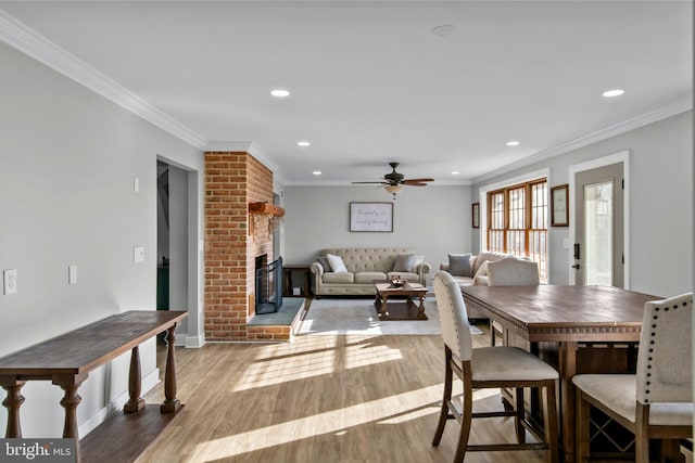 dining space with wood finished floors, recessed lighting, crown molding, a brick fireplace, and ceiling fan