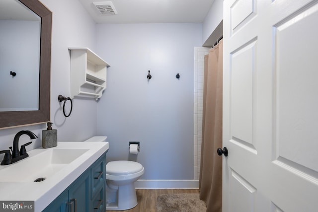 bathroom featuring visible vents, baseboards, toilet, wood finished floors, and vanity