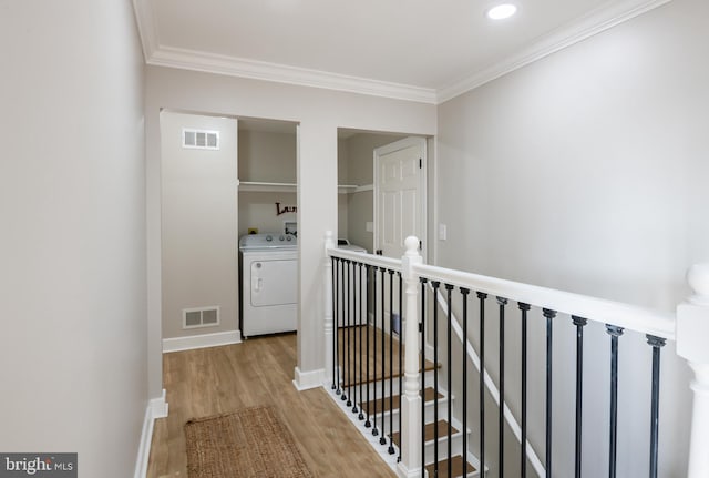 corridor featuring light wood-style flooring, washer / clothes dryer, an upstairs landing, and visible vents