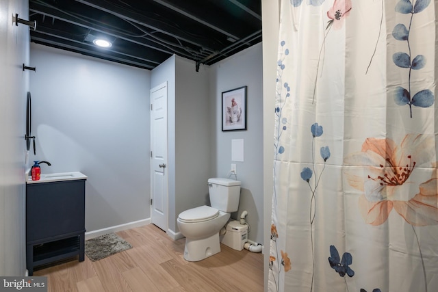 bathroom with toilet, wood finished floors, a shower with shower curtain, baseboards, and vanity