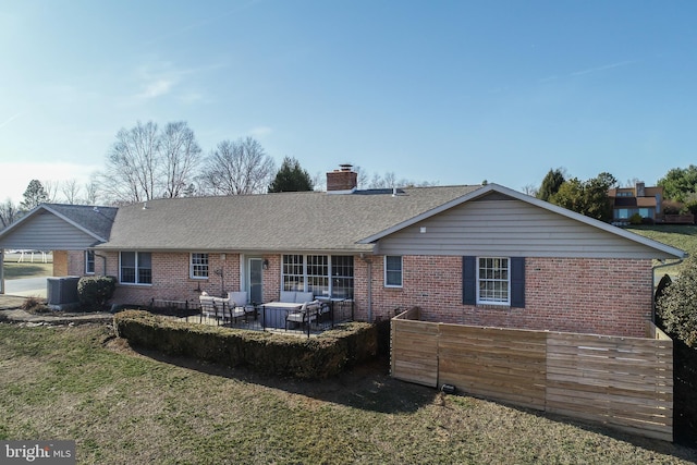 back of house featuring brick siding, roof with shingles, and a chimney