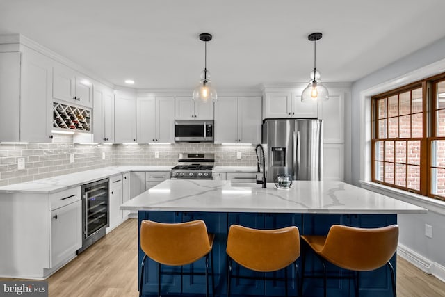 kitchen with wine cooler, white cabinets, appliances with stainless steel finishes, and a sink